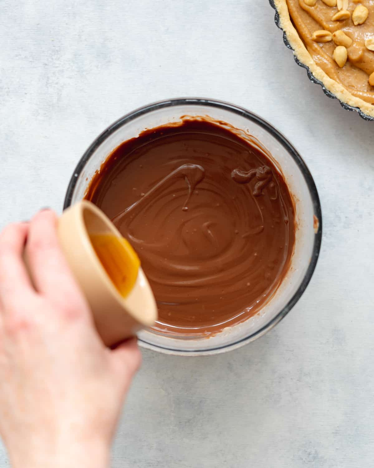 pouring maple syrup into a bowl with melted chocolate.