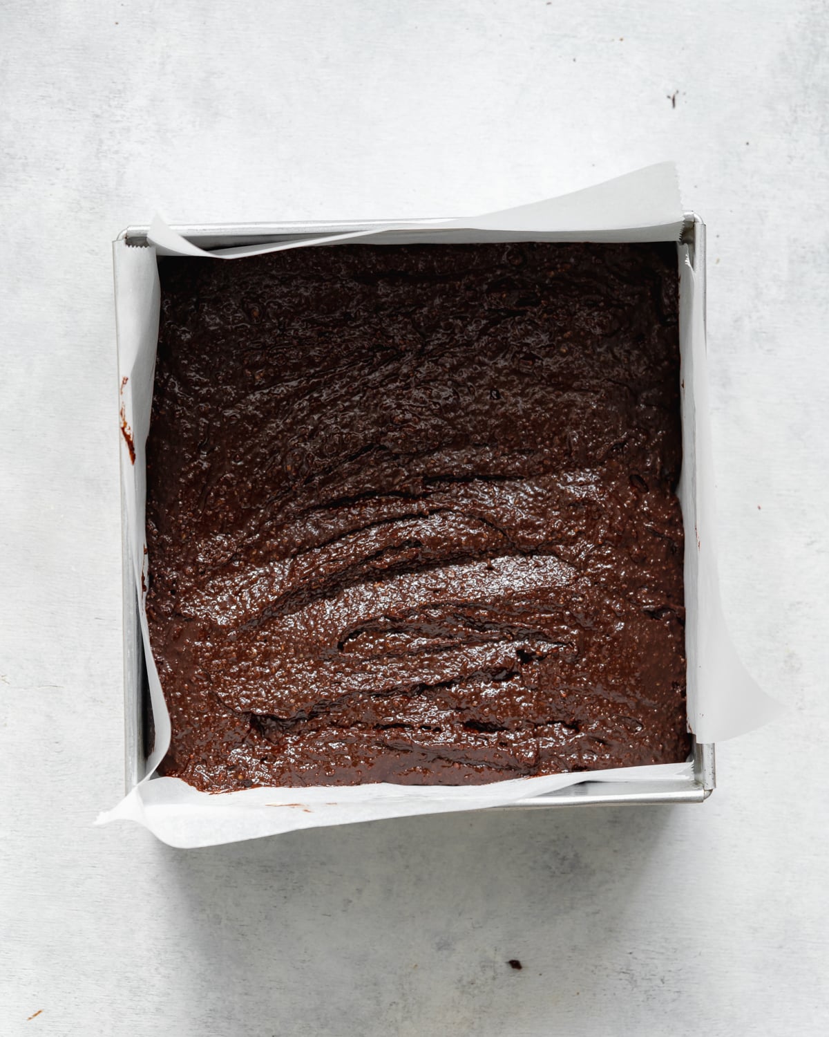 brownie batter in a lined square pan.