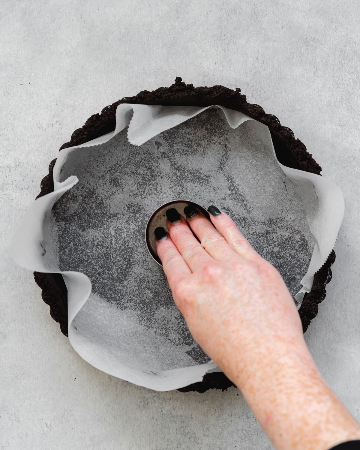 pressing oreo crust into a tart tin.