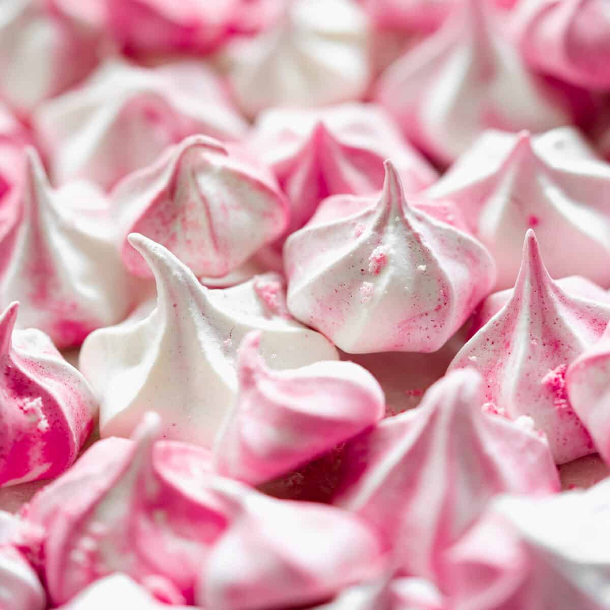 close up of pink and white meringue kisses with aquafaba.