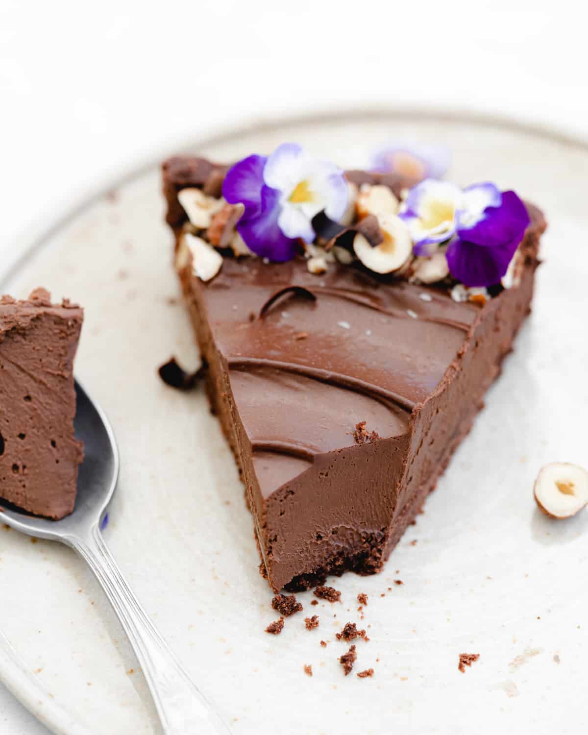 slice of chocolate hazelnut tart with edible purple flowers.