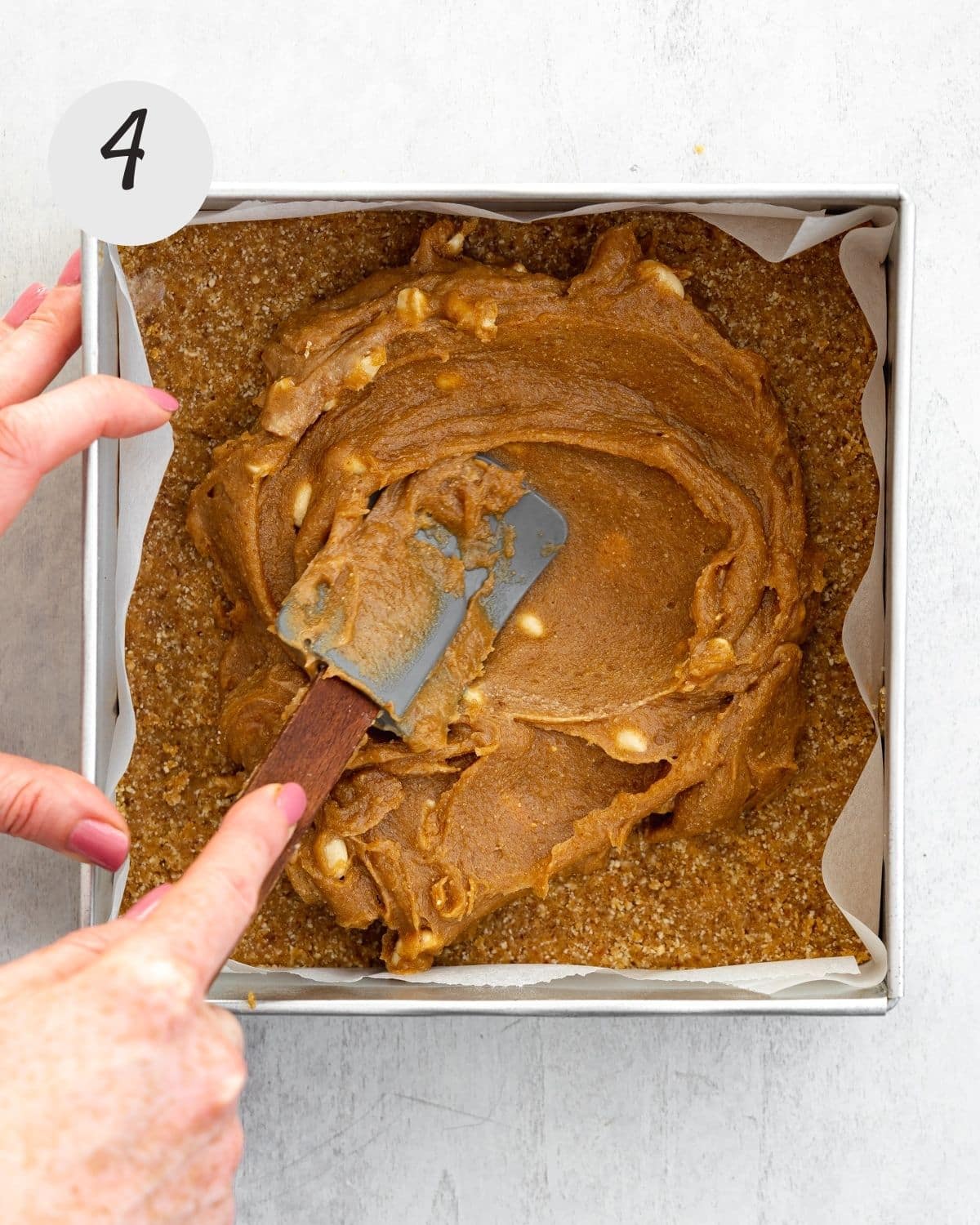 smoothing caramel into a cake tin with a spatula.