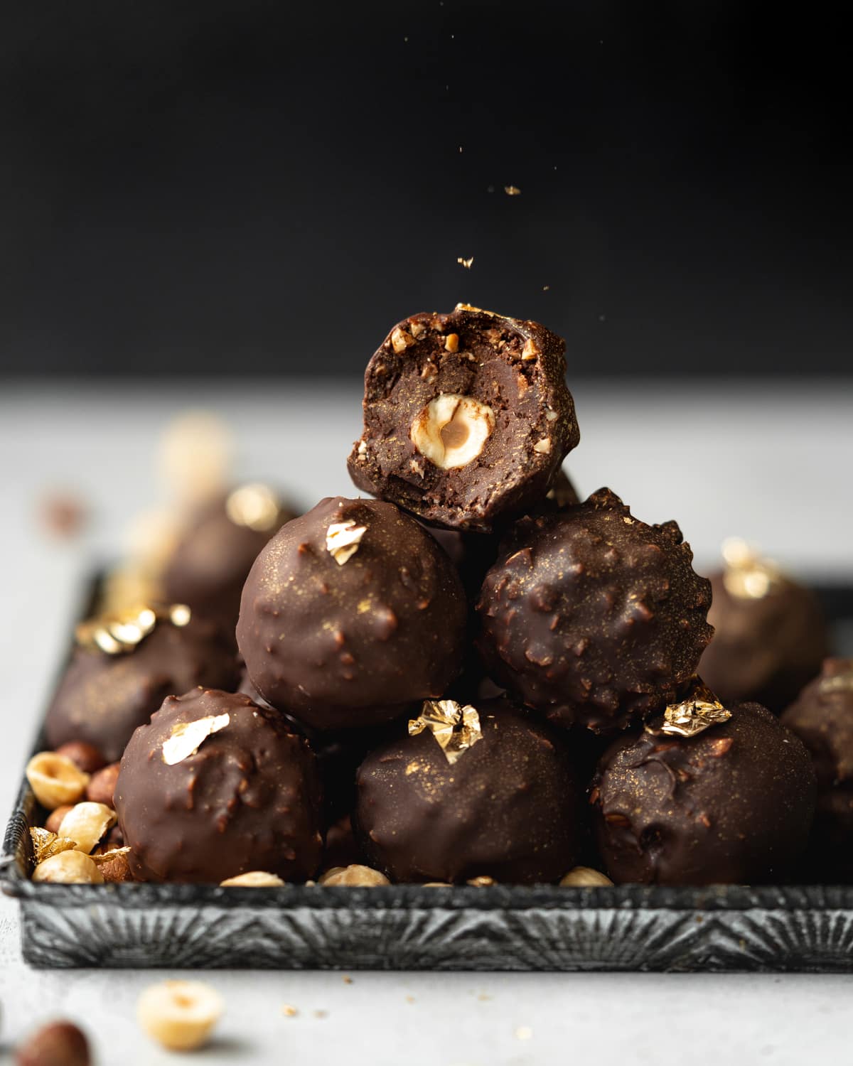 stack of vegan ferrero rochers on a metal tray with dark background.