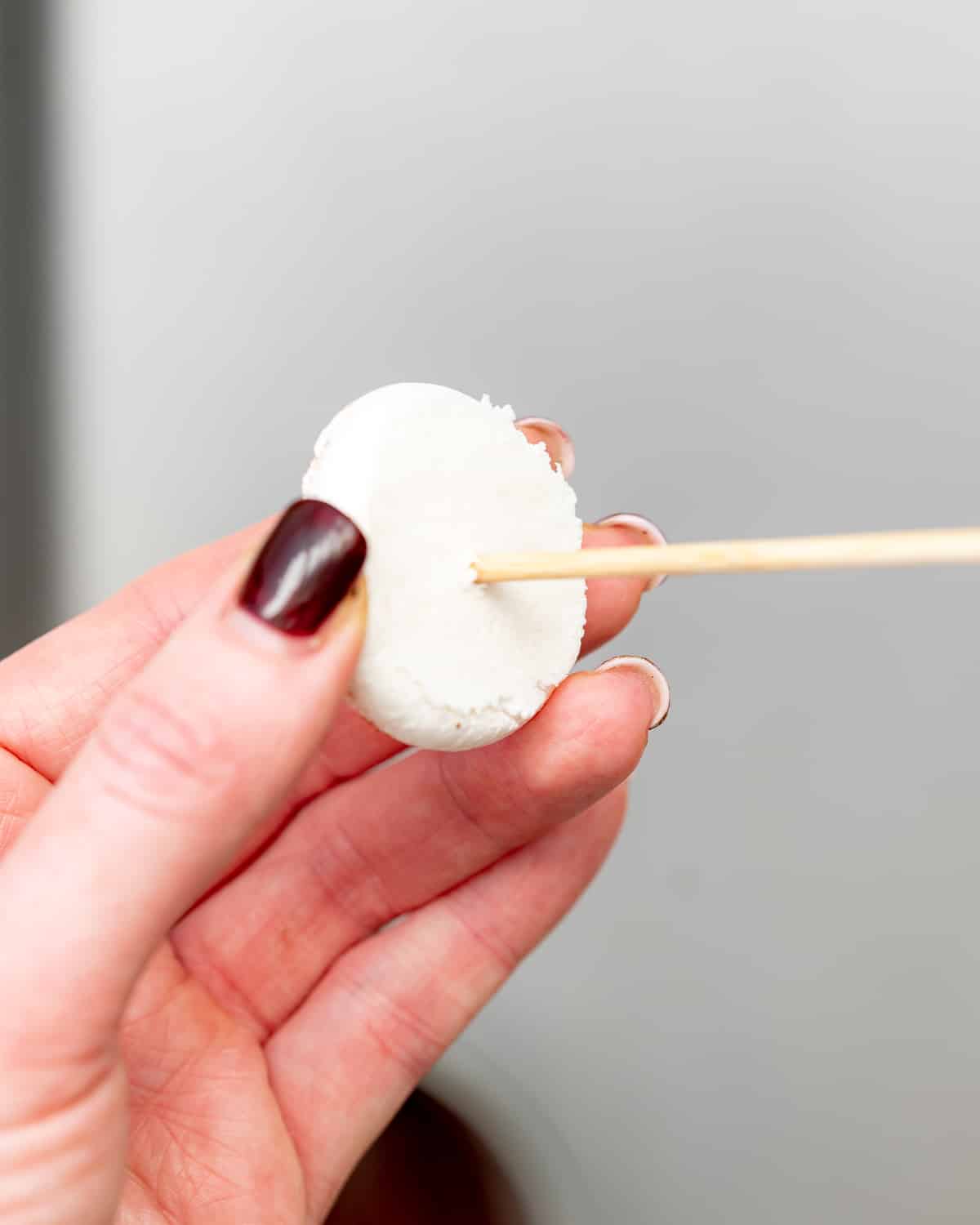 piercing hole into mushroom meringue cookie using a skewer.