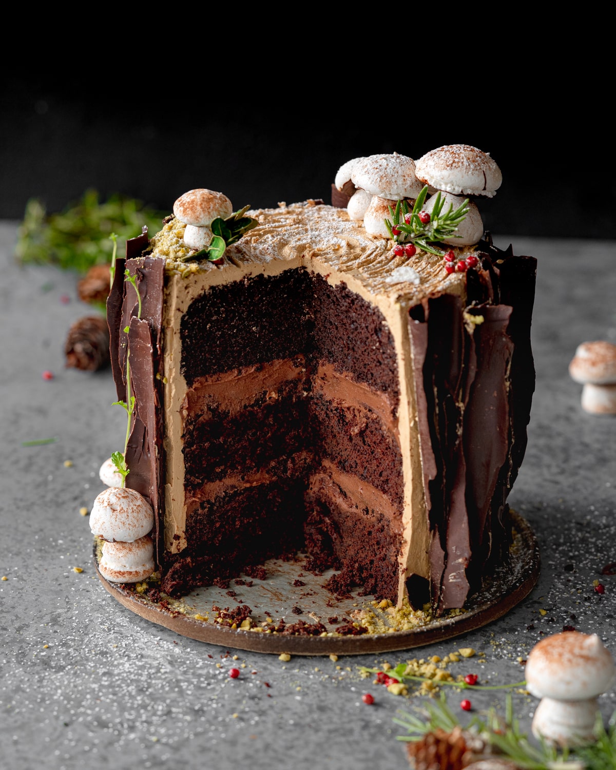 chocolate tree stump cake with layers of chocolate cremeux filling, chocolate bark and meringue mushrooms on top.